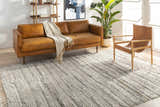 Living room scene with a charcoal and gray Saundersfoot Area Rug, leather sofa, and modern chair. Roomscene-Rectangle