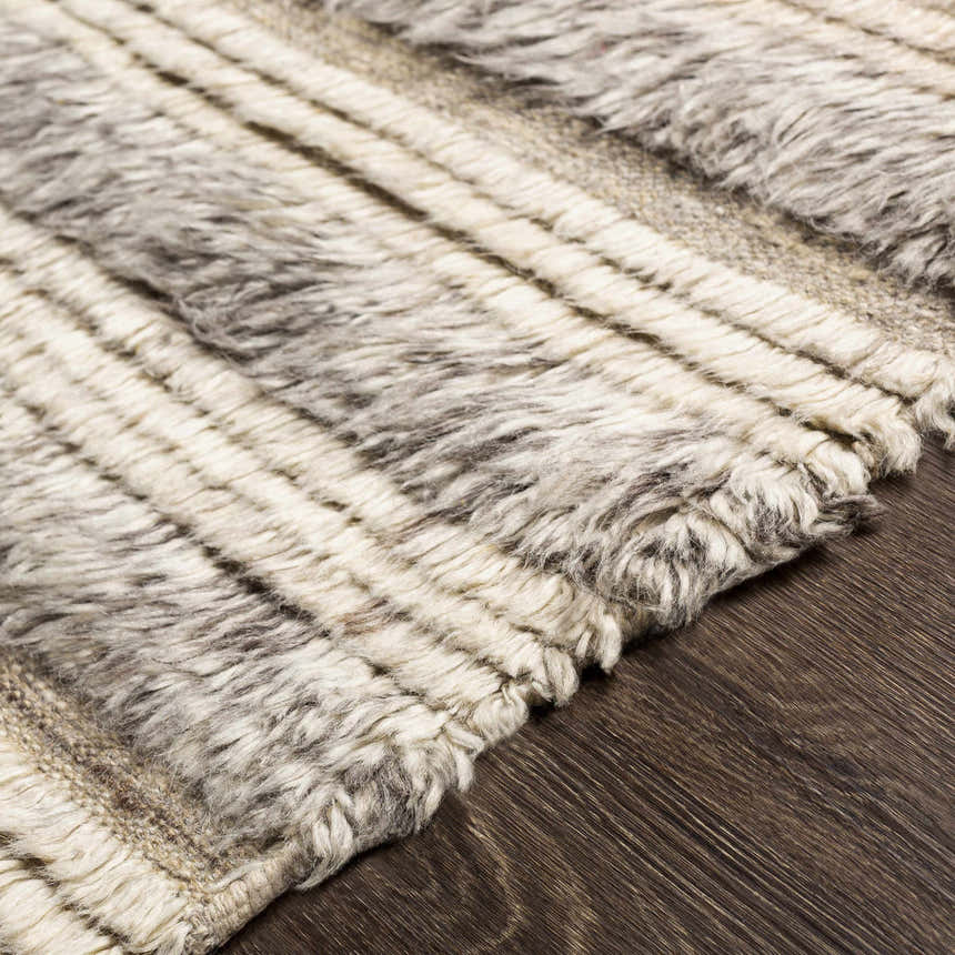 Close-up of the Saundersfoot Area Rug. Hand-knotted wool rug with a striped pattern in charcoal, gray, and light beige. Texture