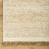 Close-up of the hand-woven Gopi Jute&Wool Area Rug in Cream, showing its texture and jute fringe detail. Corner
