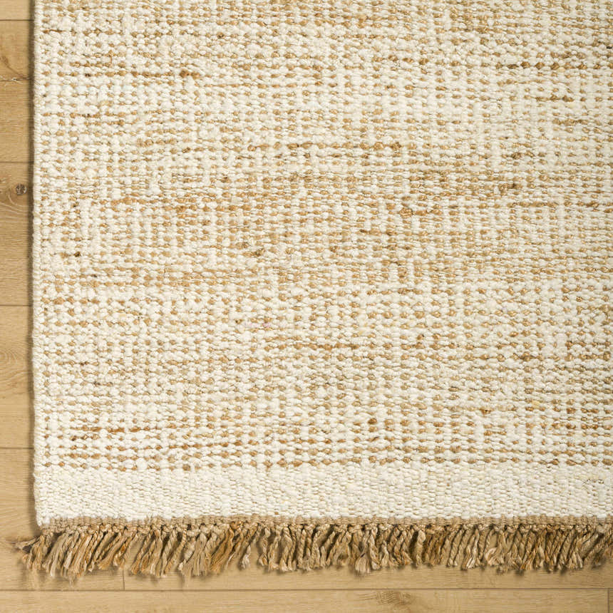 Close-up of the hand-woven Gopi Jute&Wool Area Rug in Cream, showing its texture and jute fringe detail. Corner