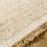 Close up of the beige Gopi Jute Area Rug showing its woven texture and knotted fringe detail. Texture