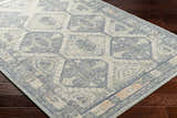 Close-up of the Doman Area Rug showing its traditional geometric pattern and wool texture in gray, blue, and cream. Corner
