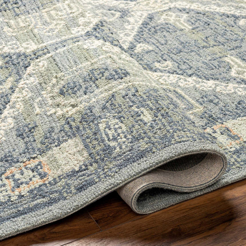 Close-up of the hand-tufted Doman Area Rug. Farmhouse style rug with dark brown, gray, and light purple tones. Wool rug texture. Fold
