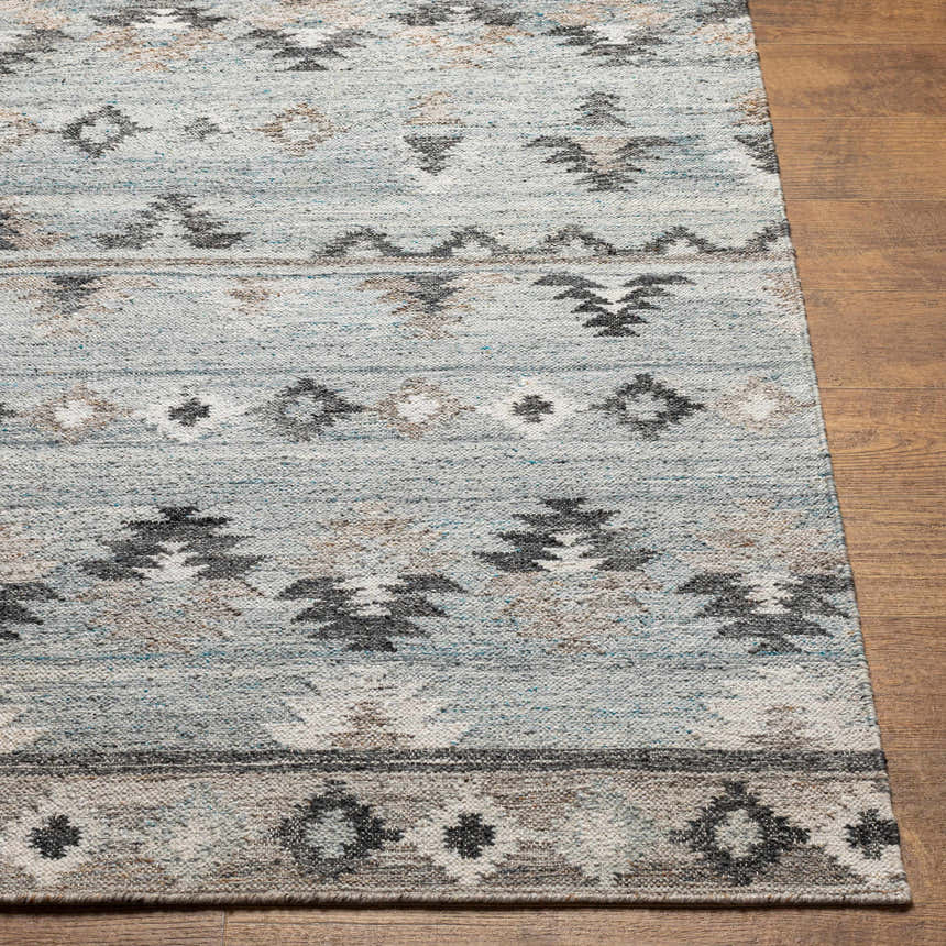 Close up of the hand woven Denna Area Rug. Southwestern design in black, blue, brown, and gray recycled PET yarn. Front