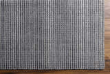 Close-up of the textured Laila Light Charcoal Area Rug showing its hand-knotted wool construction and medium gray color. Corner