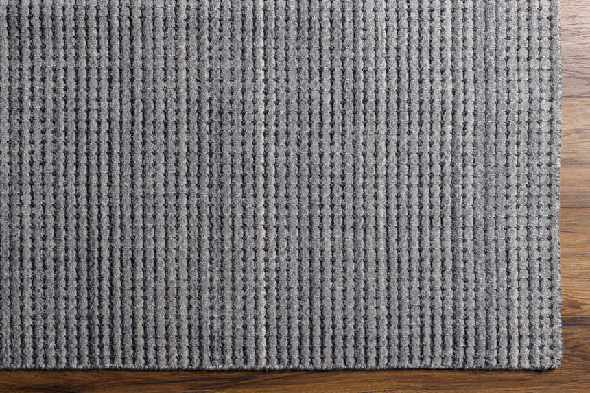 Close-up of the textured Laila Light Charcoal Area Rug showing its hand-knotted wool construction and medium gray color. Corner