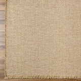 Close-up of the Kimi Jute Beige Area Rug showing its woven texture and fringed edge on a wood floor. Swatch