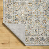 Close-up of the Jeven Blue Area Rug showing its traditional beige, blue, and gold pattern and soft texture. Fold