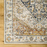 Close-up of the Kuruk Area Rug showing its farmhouse design, light gray, natural gray, and gold colors. Corner