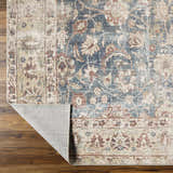 Close-up of the Marlene Damask Beige & Navy Area Rug showing its floral pattern and color variations on a wood floor. Fold