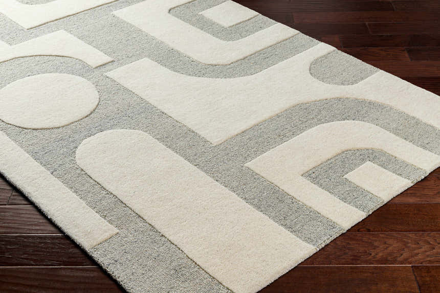 Close-up of the hand-tufted Adeja Area Rug. Contemporary design in cloud gray and light gray wool with geometric shapes. Corner
