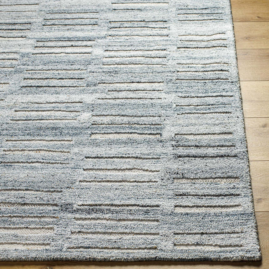 Close up of the hand-tufted Darcy Area Rug. Features a blue and white horizontal stripe pattern and a textured design. Front