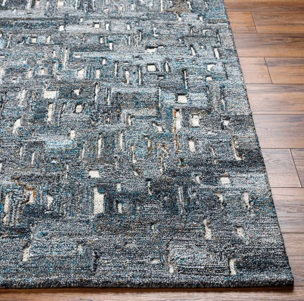 Close-up of the Fina Area Rug showing a gray, white, and blue geometric pattern and hand tufted texture. Front