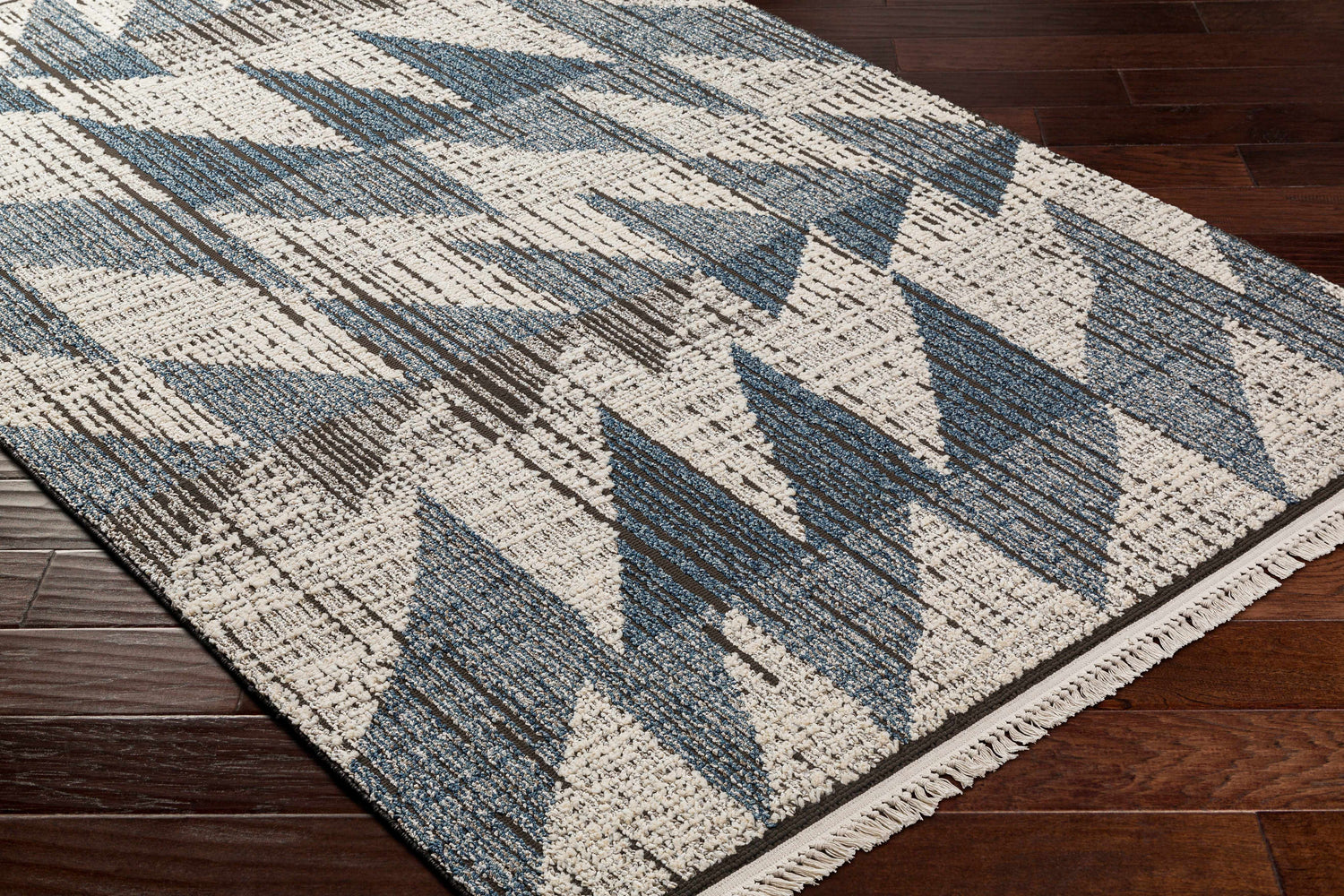 Close-up of Zaim Area Rug. Bohemian style rug with a geometric pattern in shades of blue, brown and white. Corner