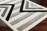 Close up of the Abeje Black & White Area Rug showing its shag texture and geometric black, gray, and off-white pattern. Corner