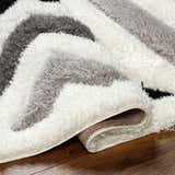 Close-up of the Abeje Black & White Area Rug, showcasing its shag texture and modern black, gray, and off-white striped design. Fold