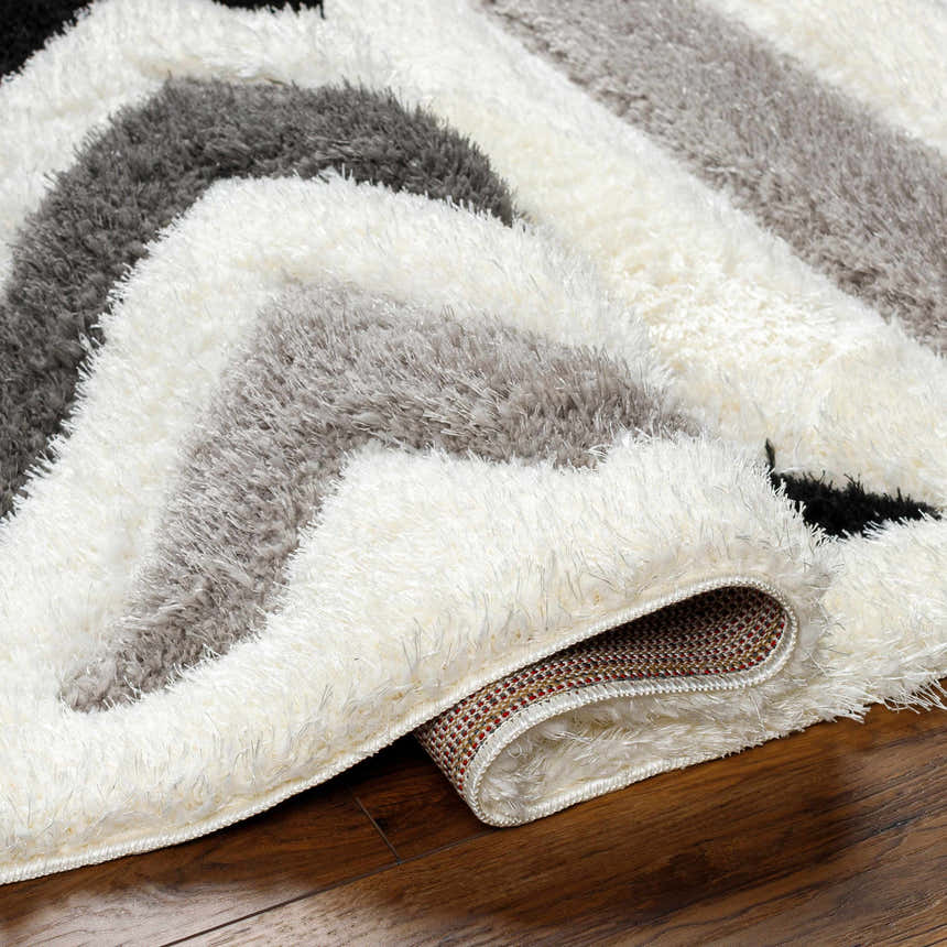 Close-up of the Abeje Black & White Area Rug, showcasing its shag texture and modern black, gray, and off-white striped design. Fold