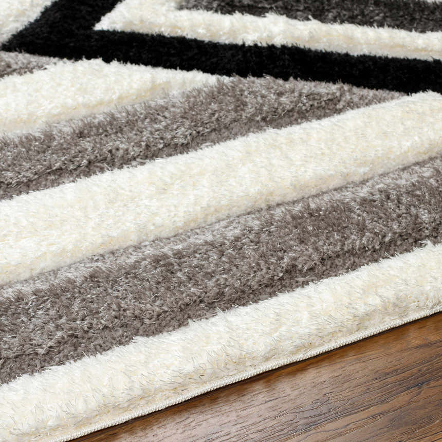 Close-up of Abeje Black & White shag rug featuring black, gray, and off-white stripes with a soft, textured pile. Texture