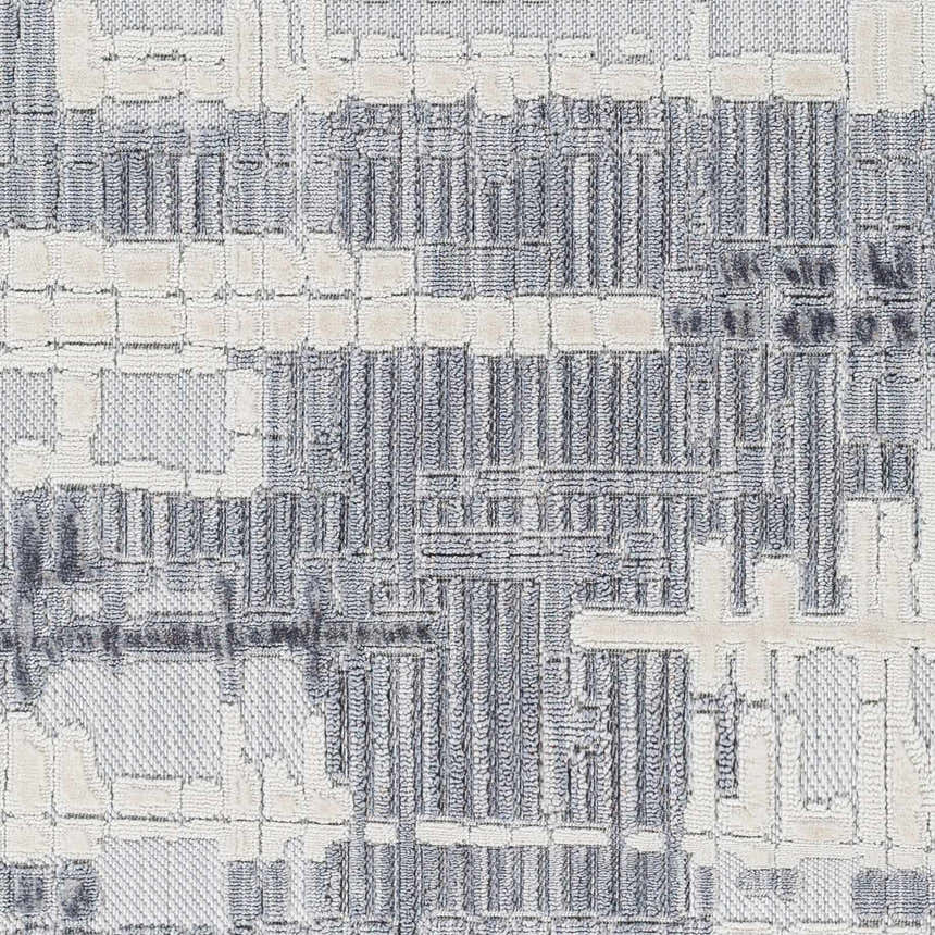 Close-up of the Bodhi Textured Saxony Rug. Features a geometric pattern in charcoal, dark gray, light gray, and white. Swatch