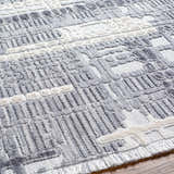 Close-up of the textured Bodhi Saxony Rug with Fringes. Gray, light gray and white geometric design. Texture