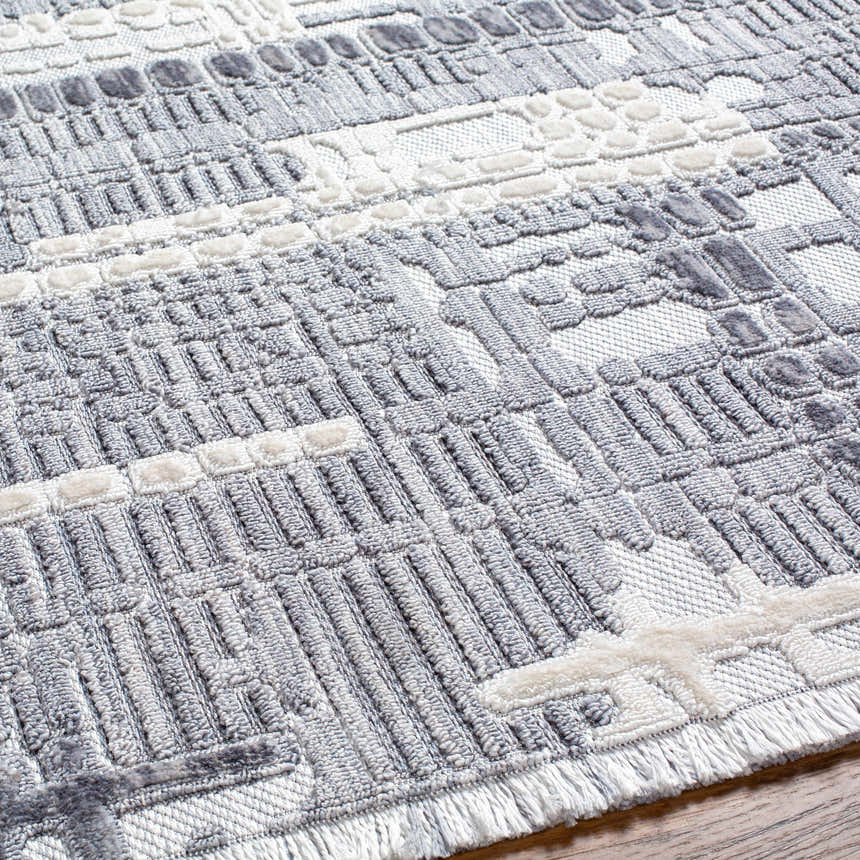 Close-up of the textured Bodhi Saxony Rug with Fringes. Gray, light gray and white geometric design. Texture