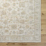 Close-up of the Sashi Tan Luxe Area Rug showing its floral, farmhouse pattern and ash, light silver, and tan colors. Corner