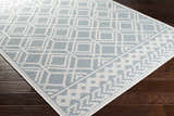 Close-up of the Scawby Area Rug. Light blue rug with a white geometric diamond pattern on dark wood flooring. Corner