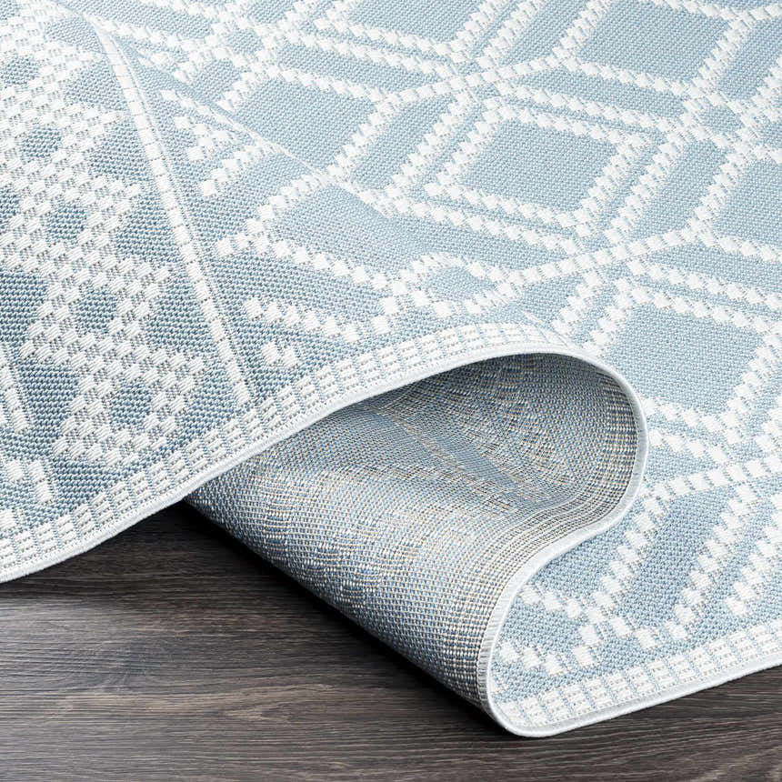 Close-up of the Scawby Area Rug showing a light blue and white geometric diamond pattern and woven texture. Fold