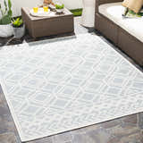 Outdoor patio scene with a light blue and white geometric Scawby Area Rug, wicker furniture, and potted plants. Roomscene-Rectangle
