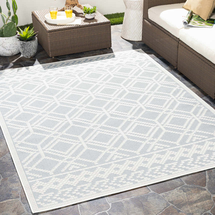 Outdoor patio scene with a light blue and white geometric Scawby Area Rug, wicker furniture, and potted plants. Roomscene-Rectangle