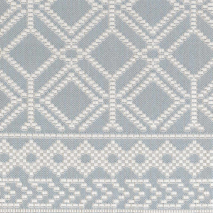 Close-up of the Scawby Area Rug. Light blue rug with a geometric diamond and border pattern. Woven texture. Swatch