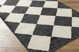 Close-up of the hand woven Sondo Jet Black Area Rug with a bold black and beige checkerboard pattern. Corner