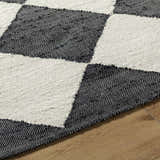 Close-up of the hand woven Sondo Jet Black Area Rug showing its black and beige checkered pattern and jute texture. Texture