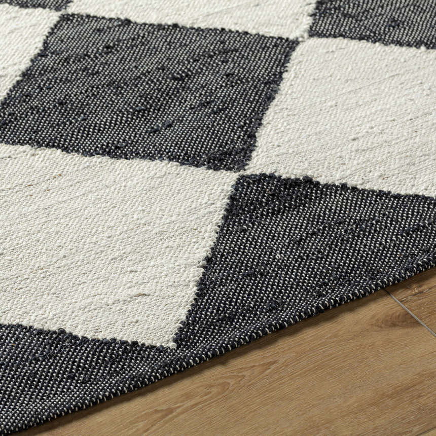 Close-up of the hand woven Sondo Jet Black Area Rug showing its black and beige checkered pattern and jute texture. Texture