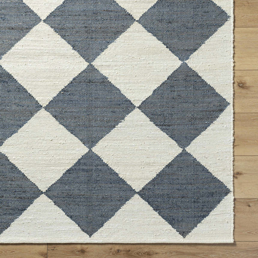 Close-up of the Sondo Off White Area Rug. Features a gray and off white diamond pattern and hand woven texture. Corner