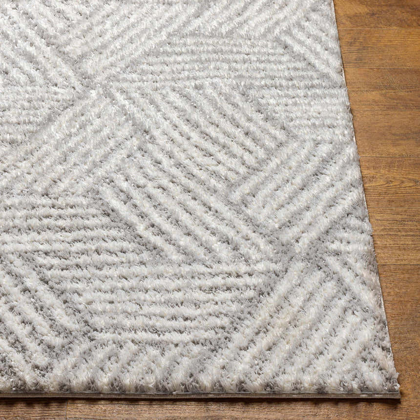Close-up of the Mura Gray Area Rug showing its geometric shag design and soft texture on a wood floor. Front
