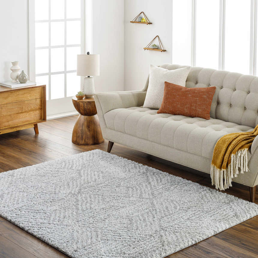 Living room scene with a beige sofa and the gray geometric Mura Area Rug on a wood floor. Roomscene-Rectangle