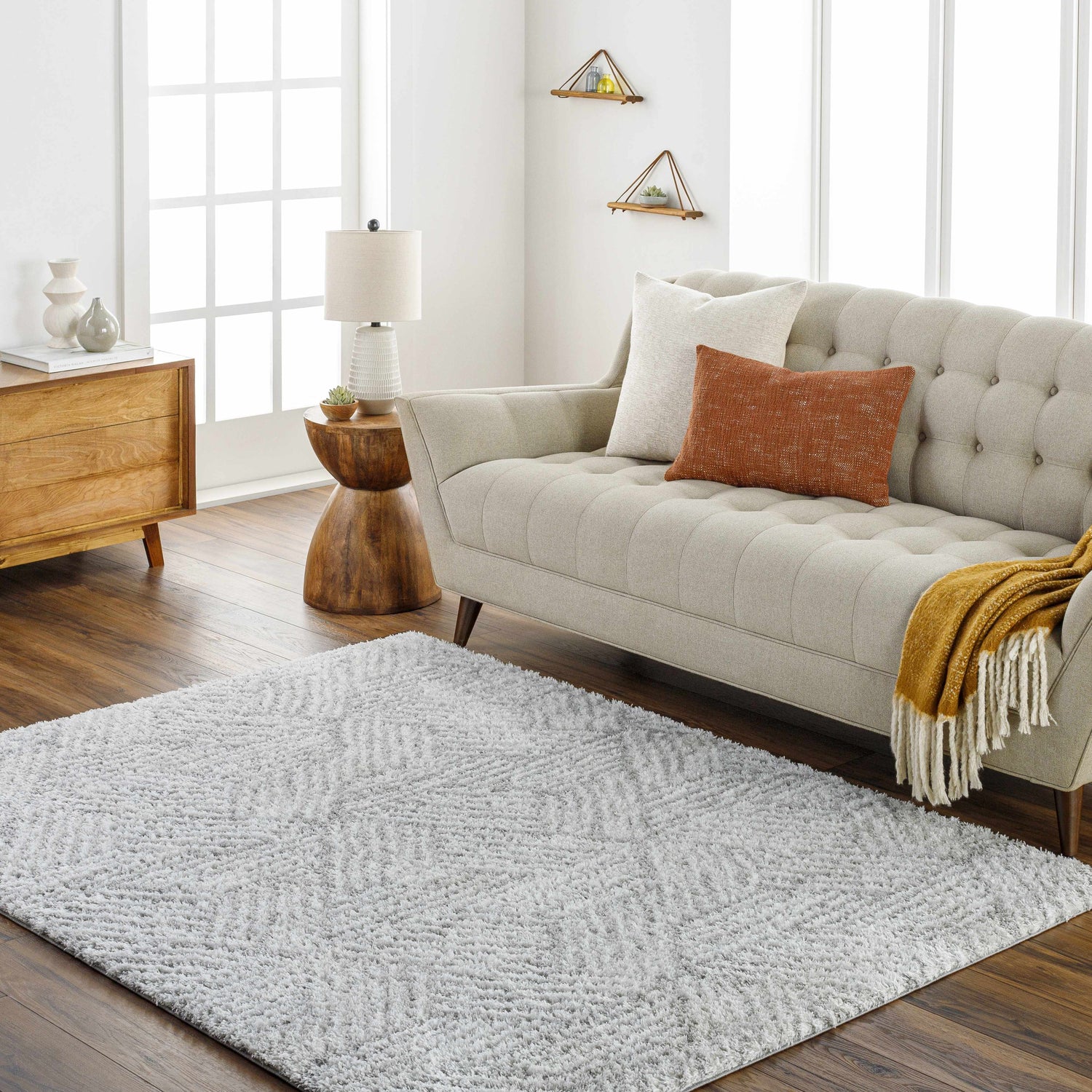 Living room scene with a beige sofa and the gray geometric Mura Area Rug on a wood floor. Roomscene-Rectangle