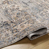 Close-up of the Addax Area Rug showing its traditional, multi-brown pattern and soft, textured polyester material. Fold
