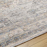 Close-up of the Addax Area Rug - Clearance. Features a traditional design in gray, blue, and brown tones. Texture