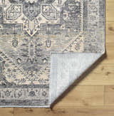 Close-up of the Ailsa Area Rug with dark gray, lambswool, and brown traditional pattern on wood floor. Fold