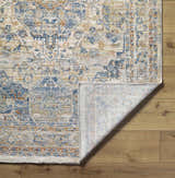 Close-up of the Bora Area Rug in camel, copper, and blue, showing the traditional pattern and machine-woven construction. Fold