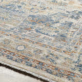 Close-up of the traditional Bora Area Rug in camel, copper, and blue. Features a machine woven construction and short fringe. Texture
