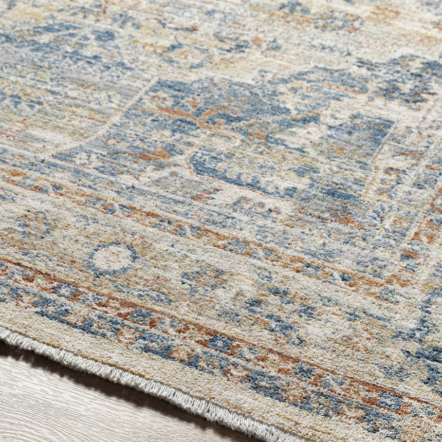 Close-up of the traditional Bora Area Rug in camel, copper, and blue. Features a machine woven construction and short fringe. Texture