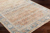 Close-up of the Dalit Area Rug. Traditional farmhouse style with clay, copper, denim, and lambswool colors. Corner