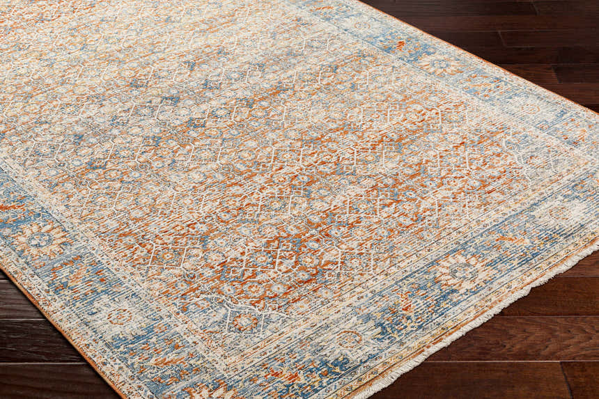 Close-up of the Dalit Area Rug. Traditional farmhouse style with clay, copper, denim, and lambswool colors. Corner
