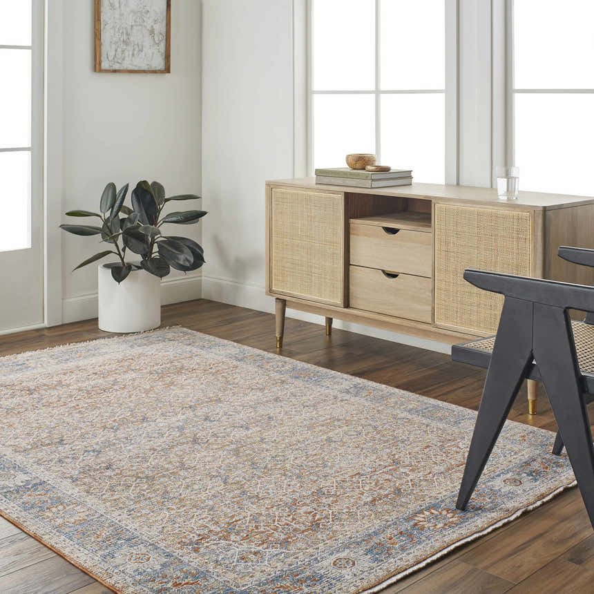 Living room scene with a clay, copper, and denim Dalit Area Rug, light wood cabinet, and modern black chair. Roomscene-Rectangle