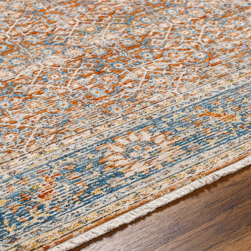 Close up of the Dalit Area Rug, showcasing its traditional clay, copper, and denim pattern on a wood floor. Texture