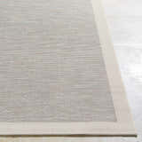 Close up of the Escalon Area Rug in cream and taupe, showing the woven texture and solid border. Front