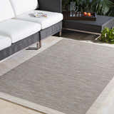 Outdoor patio scene with a taupe and cream Escalon Area Rug, wicker sofa, and coffee table. Roomscene-Rectangle